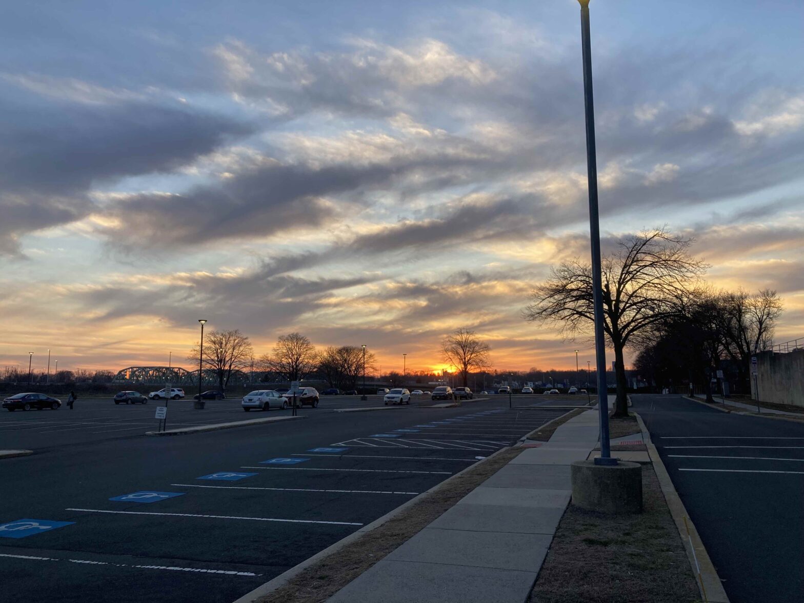 Image of a sunset over the Delaware River, from across a parking lot.