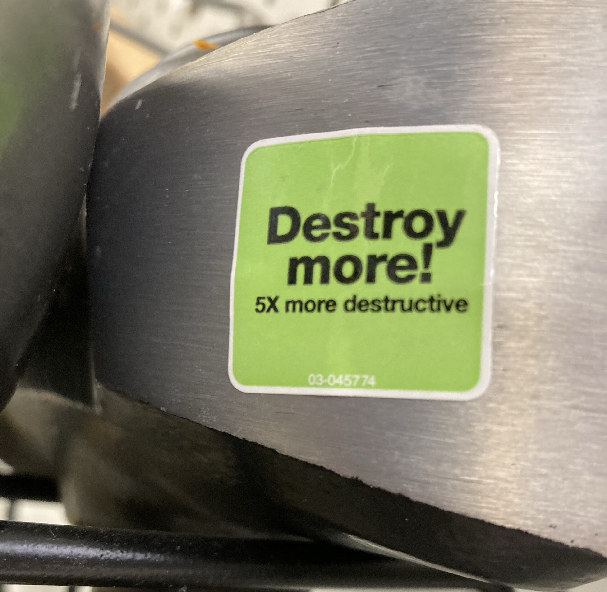 An axe head with a green sticker that says "Destroy more! 5X more destructive"